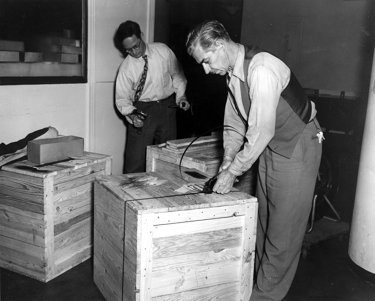Two men nail shut crates for transport