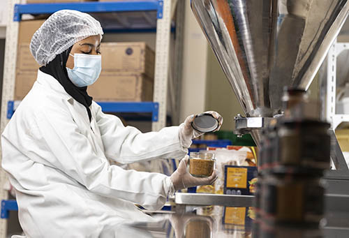 OMAN – A woman in a factory works packaging food.