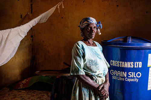 UGANDA – Una mujer almacena grano en un silo para evitar pérdidas posteriores a la cosecha..