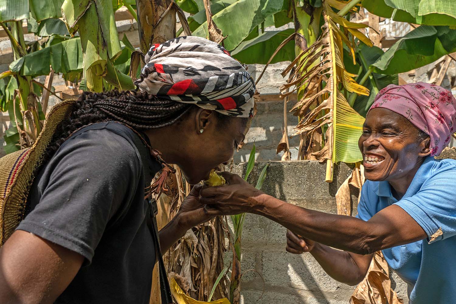 A Ghanaian woman offers another a sample of her produce