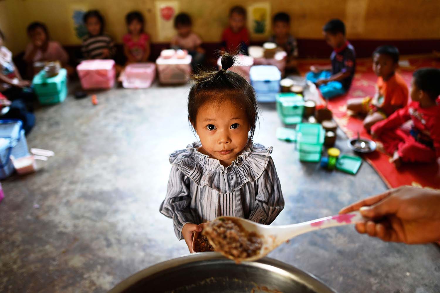 A little girl lines up for her meal in a Latin American pre-school